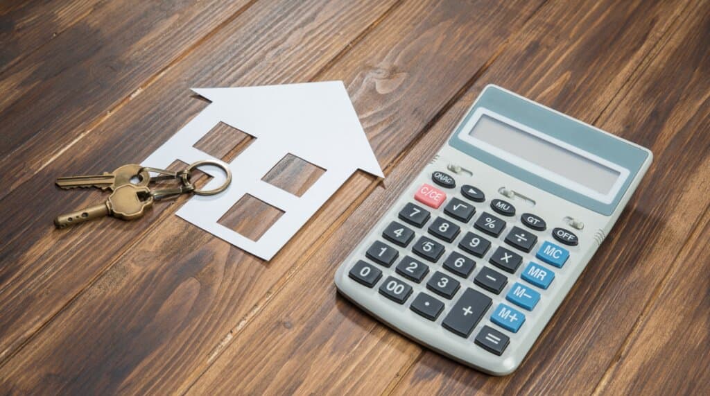 Calculatrice et maison miniature symbolisant l'estimation immobilière